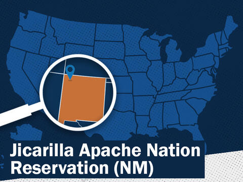 A map with a magnifying glass emphasizes a pinpoint in northwest New Mexico with text that says Jicarilla Apache Nation Reservation (NM).