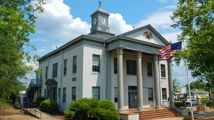 Marion County, Georgia Courthouse, a white building with four large columns and steps leading up to the front door. The American flag stands in front of the building.