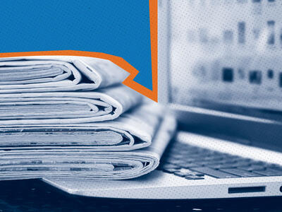 stack of newspapers resting on the keyboard of a laptop computer